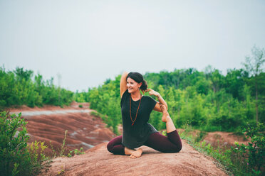 Woman doing pigeon pose on rock - ISF21150