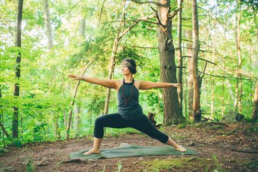 Frau macht Krieger Pose im Wald - ISF21151