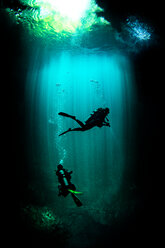 Underwater view of male and female scuba divers exploring cenote called the pit, Tulum, Quintana Roo, Mexico - ISF21174