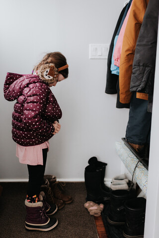 Mädchen zieht Jacke in der Garderobe an, lizenzfreies Stockfoto