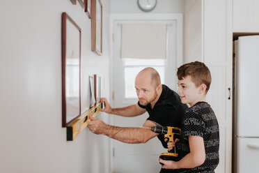 Vater lehrt Sohn, die Wand für Bilderrahmen zu bohren - ISF21204