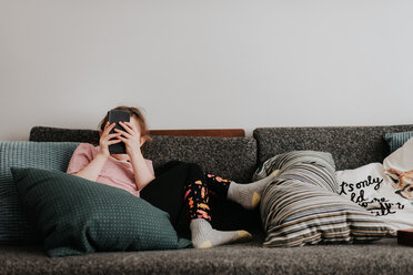 Mädchen spielt mit Smartphone auf Couch - ISF21206