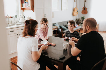 Vierköpfige Familie spielt Karten in der Küche - ISF21210