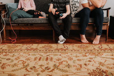 Mutter sitzt mit Kindern auf der Couch und spielt ein Videospiel - ISF21213