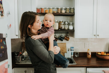 Mother carrying baby son in kitchen - ISF21220