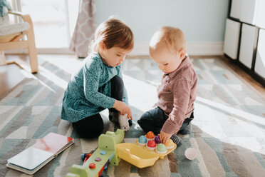 Weibliches Kleinkind spielt mit seinem kleinen Bruder im Wohnzimmer - ISF21222