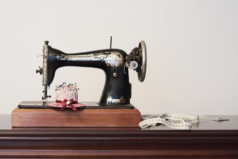 Alte Vintage-Nähmaschine mit Maßband und Stecknadeln in Form eines Hutes - IGGF01025