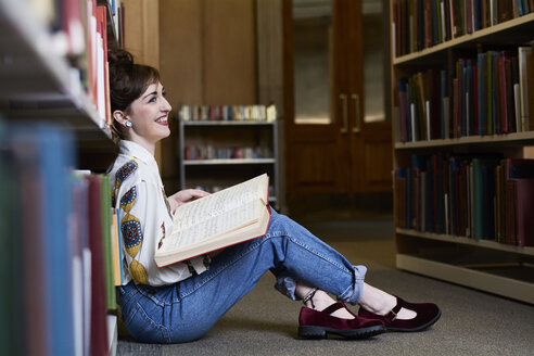 Studentin beim Lesen eines Buches in einer öffentlichen Bibliothek - IGGF01035