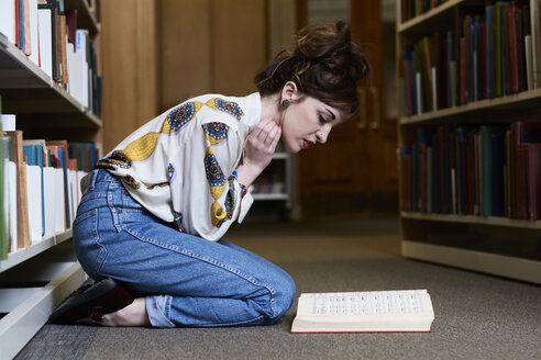 Studentin beim Lesen eines Buches in einer öffentlichen Bibliothek - IGGF01037
