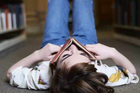 Studentin beim Lesen eines Buches in einer öffentlichen Bibliothek - IGGF01051