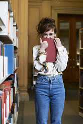 Female student reading book in a public library - IGGF01053