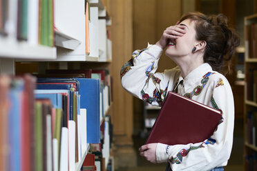 Female student reading book in a public library - IGGF01054