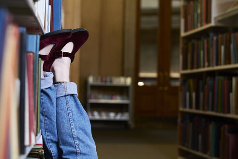 Studentin in einer öffentlichen Bibliothek, Füße hochgelegt - IGGF01059