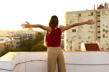 Rückansicht eines jugendlichen Mädchens auf einer Dachterrasse in der Stadt bei Sonnenuntergang - ERRF00939