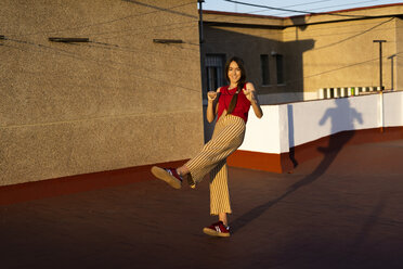 Glückliches Teenager-Mädchen tanzt auf der Dachterrasse bei Sonnenuntergang - ERRF00949