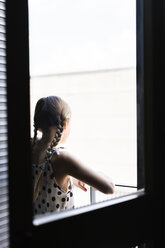 Rückansicht eines Mädchens in gepunktetem Kleid mit Blick vom Balkon - ERRF00963