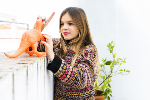 Mädchen spielt mit Dinosaurier Spielzeug zu Hause, lizenzfreies Stockfoto