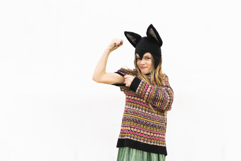 Portrait of girl flexing muscles in bat costume in front of white wall stock photo