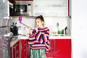 Mädchen spielt mit Mikrofon und Smartphone in der Küche zu Hause - ERRF00996