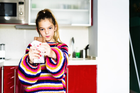 Porträt eines Mädchens im gestreiften Pullover in der Küche zu Hause, das Schokolade isst, lizenzfreies Stockfoto