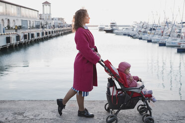 Mother pushing daughter in stroller at a marina - EYAF00128