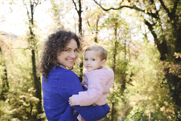 Portrait of happy mother carrying her daughter in nature - EYAF00137