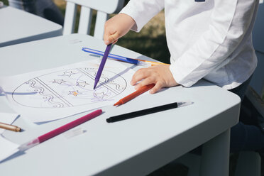 Close-up of toddler coloring Easter egg on a paper - MOMF00679