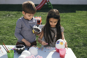 Friends painting Easter eggs in garden - MOMF00691