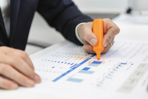 Close-up of businessman using highlighter on a report at desk in office stock photo