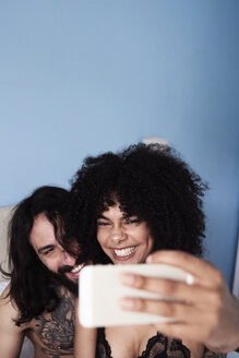 Glückliches zärtliches junges Paar, das ein Selfie im Bett macht - IGGF01069