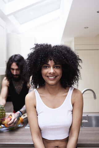 Porträt einer lächelnden jungen Frau mit ihrem Freund in der Küche, lizenzfreies Stockfoto