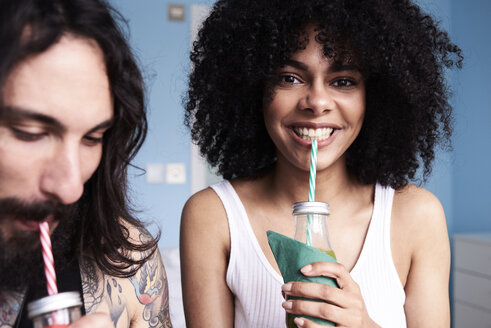 Portrait of smiling young woman with boyfriend drinking smoothie - IGGF01097