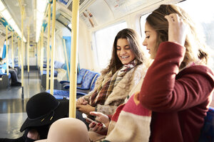 UK, London, zwei glückliche Frauen in der U-Bahn telefonieren - IGGF01107