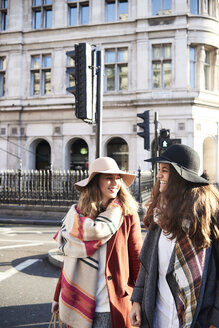 UK, London, zwei glückliche Frauen in der Stadt, die eine Straße überqueren - IGGF01112
