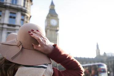 Großbritannien, London, Rückansicht einer Frau mit Schlapphut, die auf den Big Ben blickt - IGGF01116
