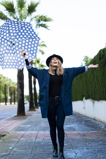 Blonde Frau mit Regenschirm an einem regnerischen Tag - ERRF01059