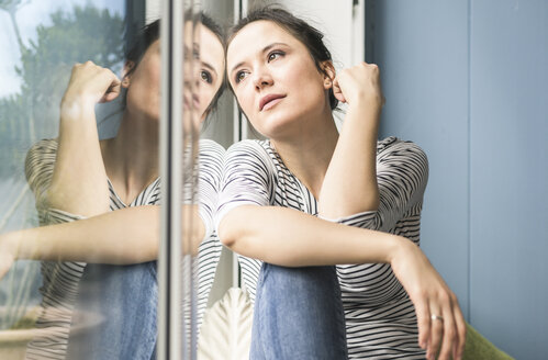 Ernste Frau schaut zu Hause aus dem Fenster - UUF17182