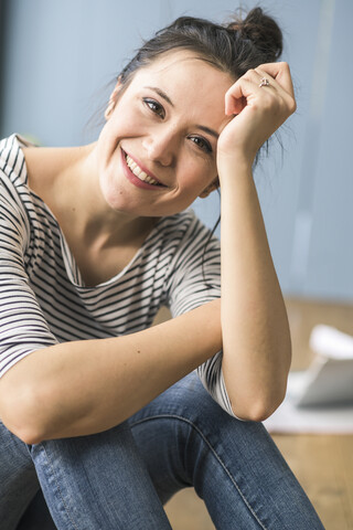 Porträt einer glücklichen Frau, die zu Hause auf dem Boden sitzt, lizenzfreies Stockfoto