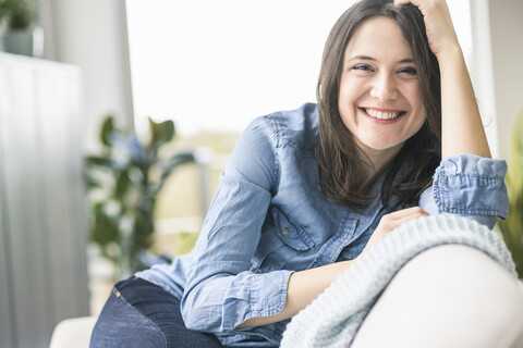 Portrait of happy woman sitting on the couch at home stock photo