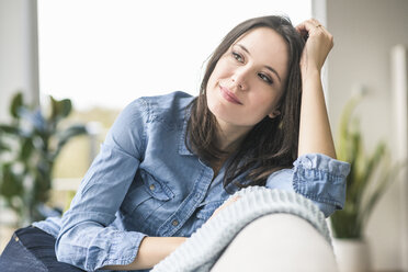 Portrait of smiling woman sitting on the couch at home - UUF17224