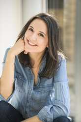 Portrait of happy woman wearing denim shirt at home - UUF17233