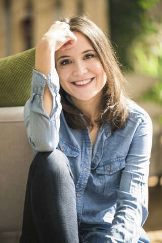 Portrait of happy woman wearing denim shirt at home stock photo