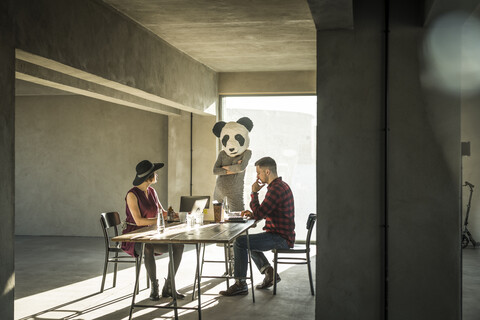 Woman with panda mask watching colleagues in office stock photo