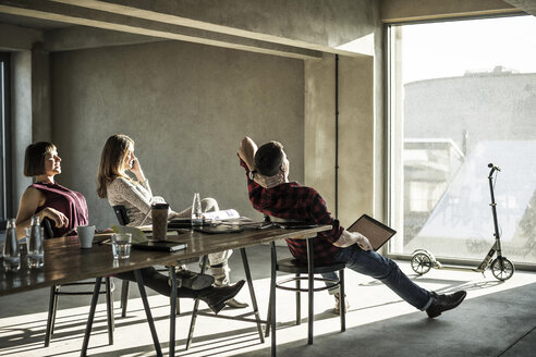 Eine Gruppe von Kreativen sitzt in ihrem Büro, schaut aus dem Fenster und genießt die Sonne - MJRF00154