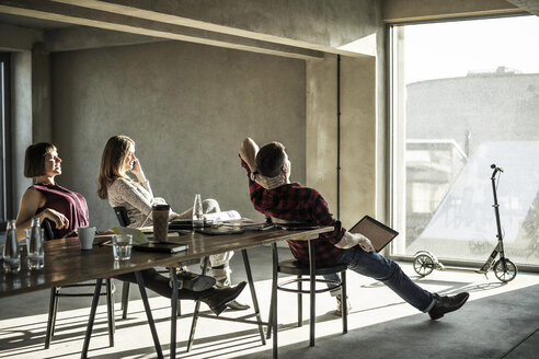 Group of creative professionals sitting in their office, looking out of the window, enjoying the sun - MJRF00154