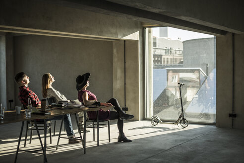Eine Gruppe von Kreativen sitzt in ihrem Büro, schaut aus dem Fenster und genießt die Sonne - MJRF00156