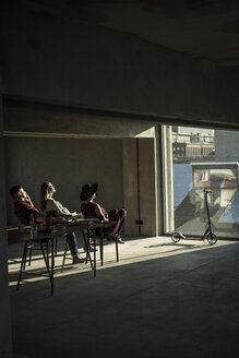 Eine Gruppe von Kreativen sitzt in ihrem Büro, schaut aus dem Fenster und genießt die Sonne - MJRF00162
