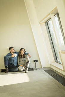 happy couple, expecting baby, sittig on floor of their new apartment - MJRF00167