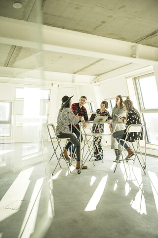 Eine Gruppe von Kreativprofis trifft sich in einem hellen Büro und bespricht neue Lösungen, lizenzfreies Stockfoto