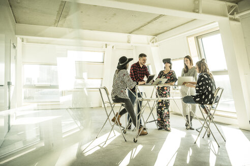 Eine Gruppe von Kreativprofis trifft sich in einem hellen Büro und bespricht neue Lösungen - MJRF00191